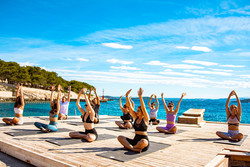 Joga poteka na plaži ali v senci borovcev.